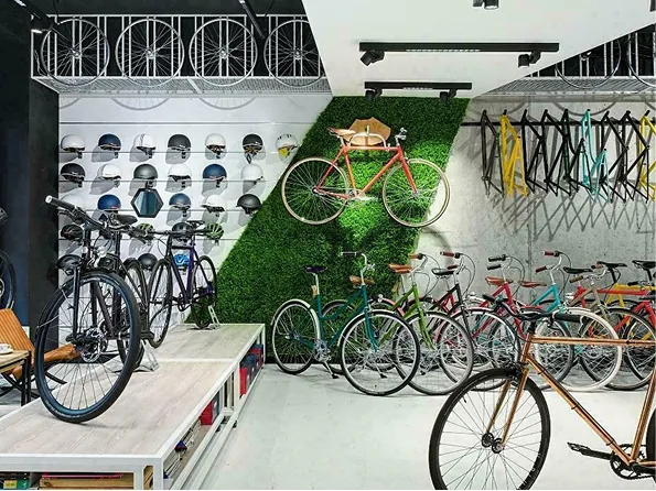 Wnętrze sklepu rowerowego z rzędem rowerów i zieloną ścianą z zawieszonym czerwonym rowerem