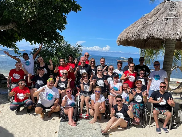 Grupa wolontariuszy i uczestników Fundacji Mniejszy Błękit pozująca na plaży przy morzu