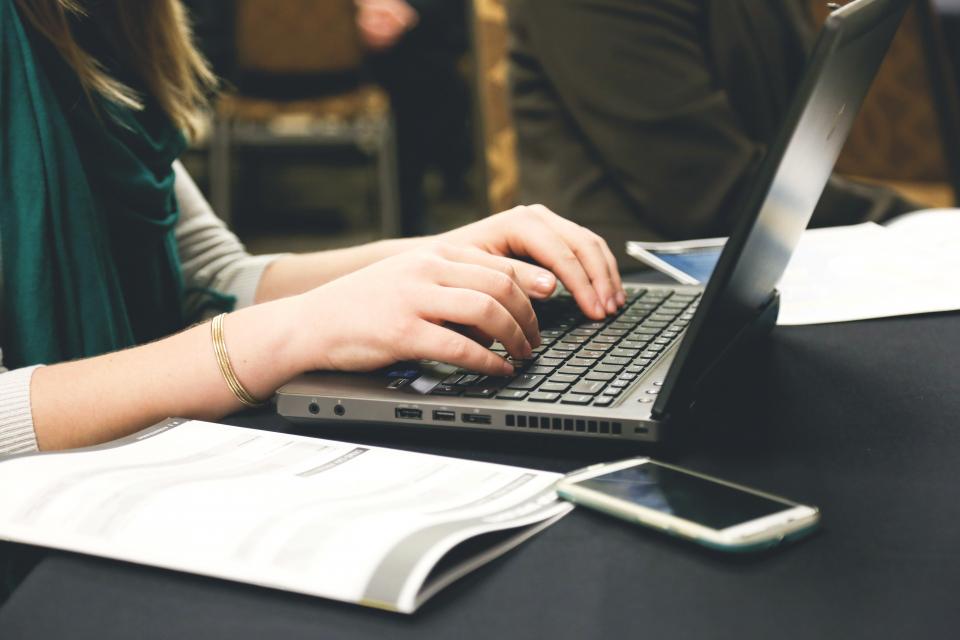 Kobieta pisząca na klawiaturze laptopa przy stole